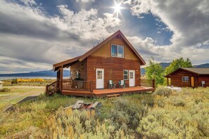 A wooden cabin with a porch, two windows, and a deck.