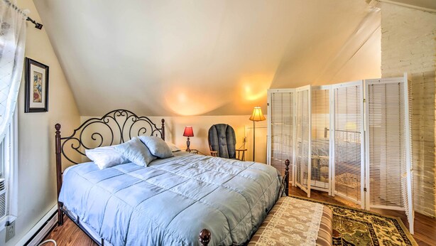 Een slaapkamer met een bed, een stoel, een lamp en een raam met zonwering.