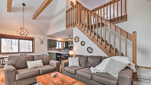 A spacious living room with two sofas, a wooden coffee table, and a staircase with wooden railings.