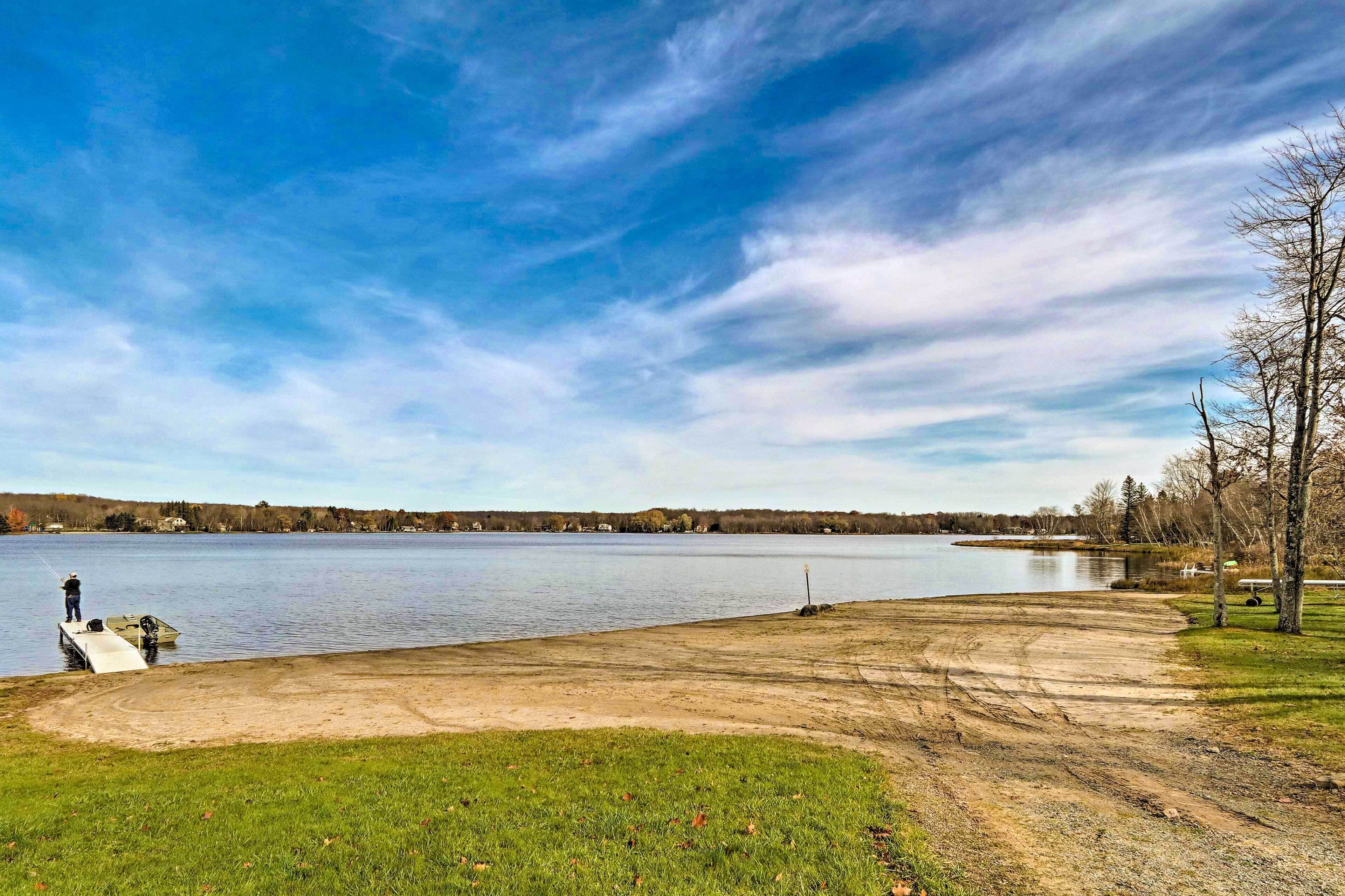A lakeside view with a boat dock, grassy area, and trees.