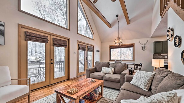 A spacious living room with a large window, a wooden coffee table, and a gray sofa.