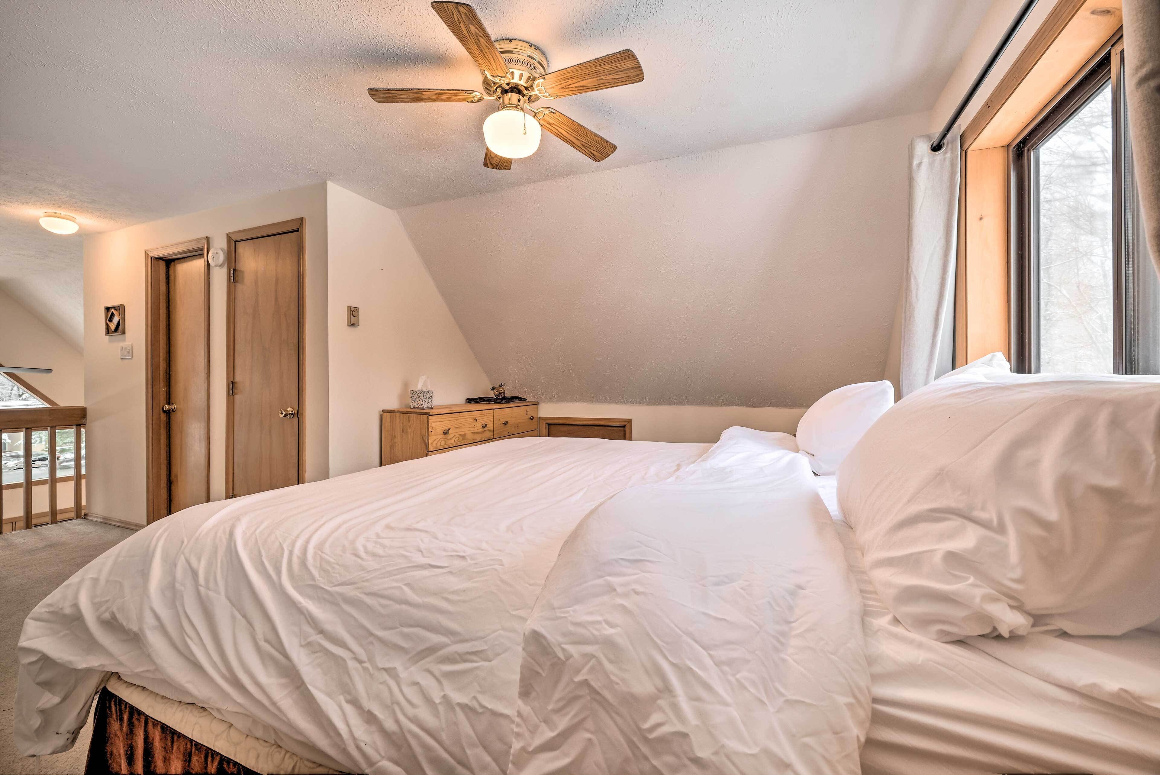Un dormitorio con cama, ventilador de techo, ventana y puerta.