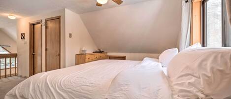 Une chambre à coucher avec un lit, un ventilateur de plafond, une fenêtre et une porte.