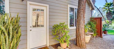 A house with a white door, a small porch with potted plants, and a wooden fence.