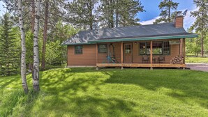 A cabin with a porch, a chimney, and a stack of firewood. - Lead Cabin ~ 9 Mi to Deadwood: Hot Tub + Patio! (Lead)