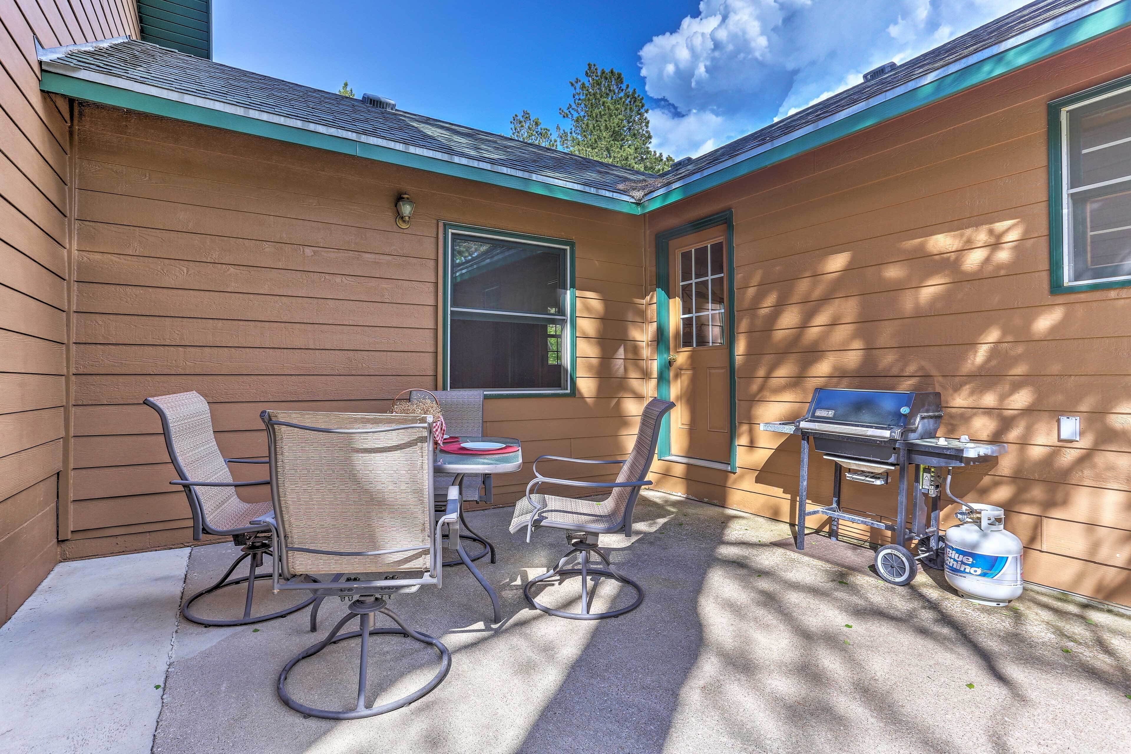 Un patio con mobiliario exterior, una parrilla y tanque de propano.