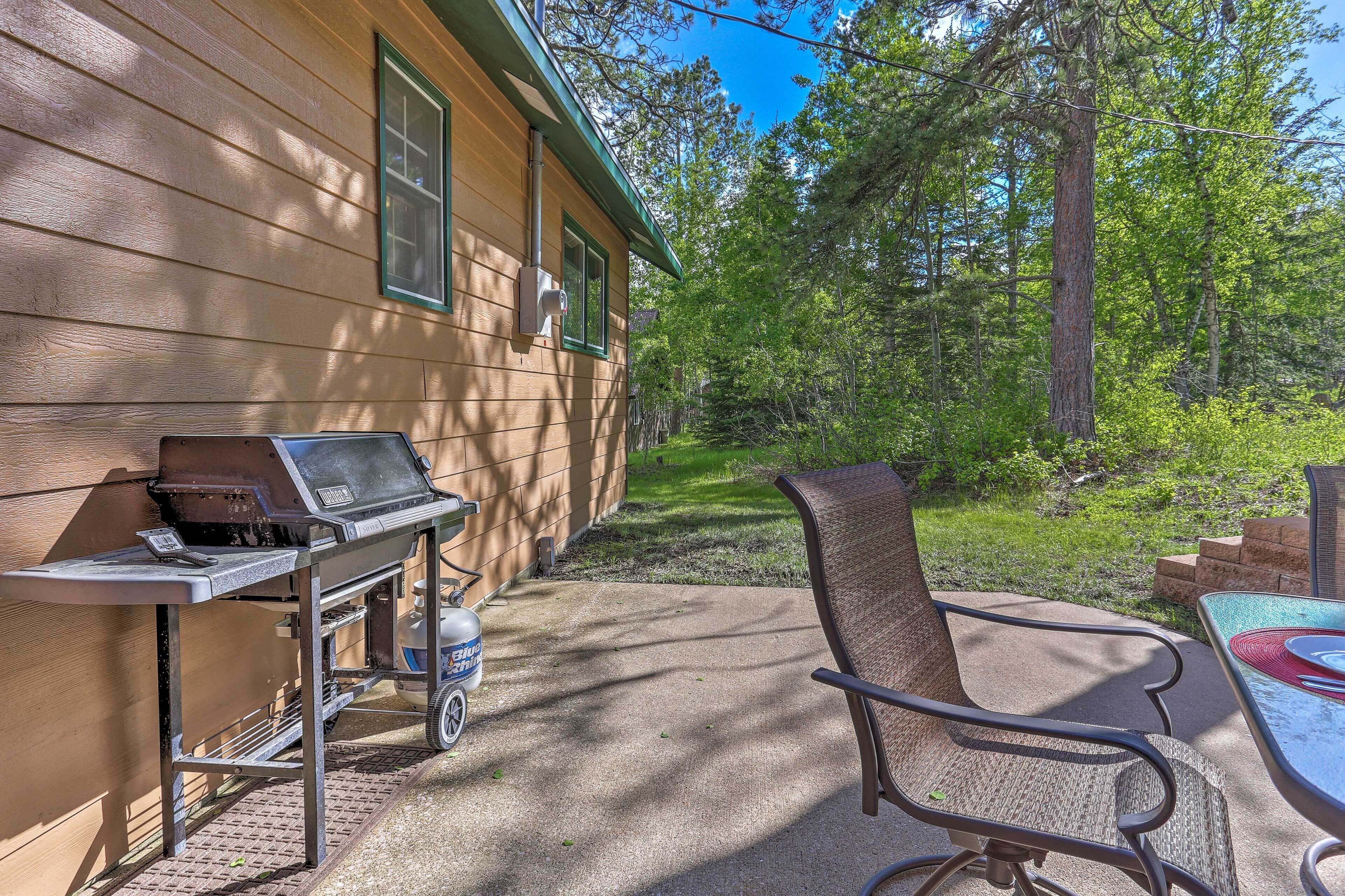 Un patio exterior con una parrilla, una silla y una mesa.