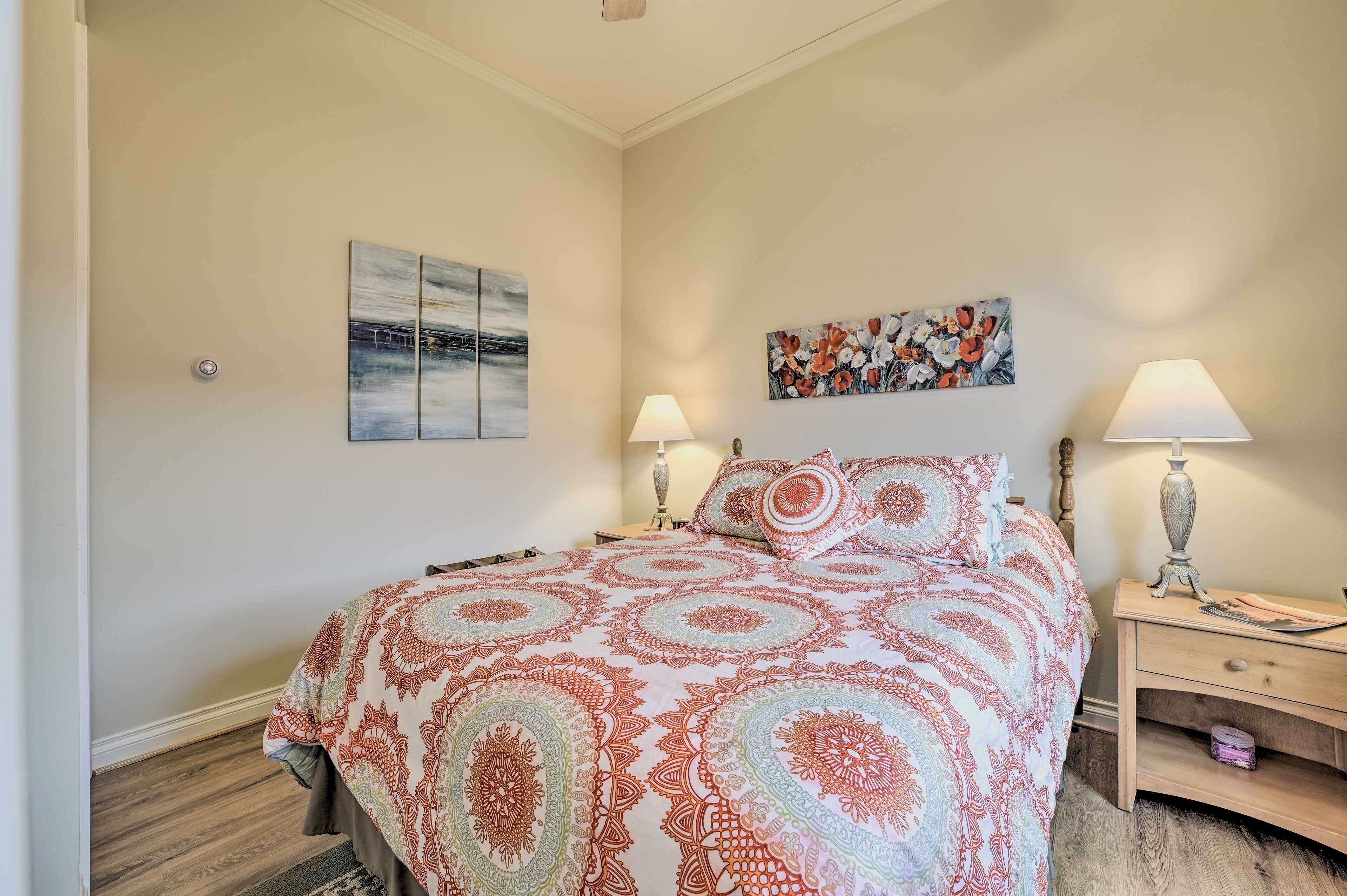 Un dormitorio con una cama grande, dos mesitas de noche, una lámpara de pared y dos obras de arte en la pared.