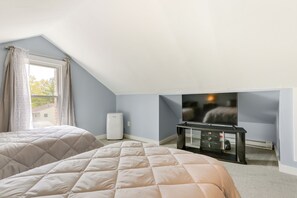 Une chambre avec deux lits, une télévision, un radiateur et une fenêtre avec des rideaux.
