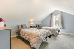 Une chambre avec deux lits, un bureau, une lampe et une fenêtre avec des rideaux.