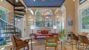 Un salon spacieux avec un escalier, une grande fenêtre et un coin repas.
