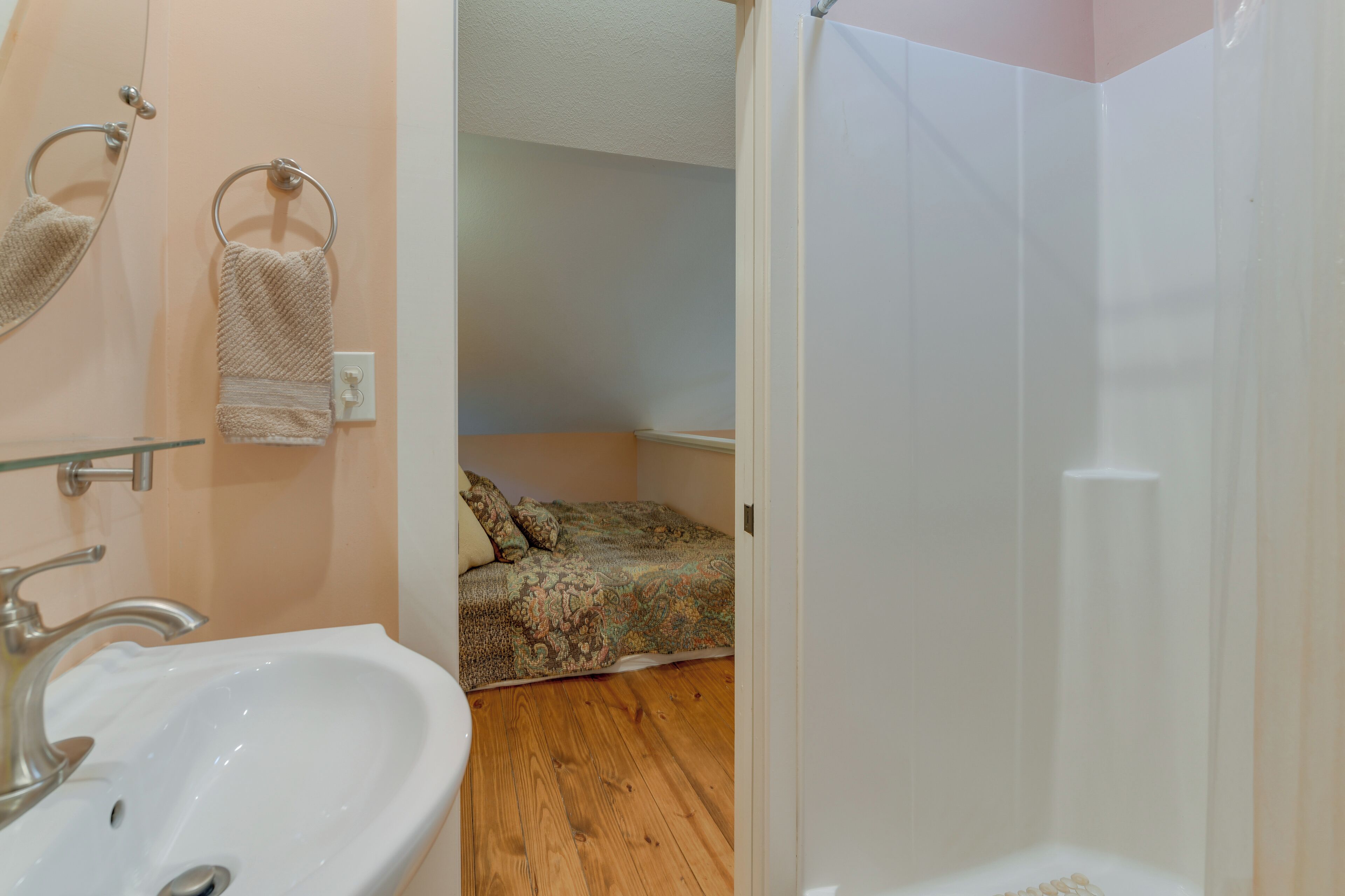 A bathroom with a sink, towel rings, and a shower area.