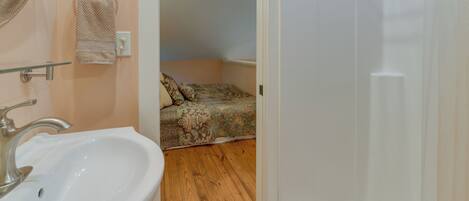 A bathroom with a sink, towel rings, and a shower area.