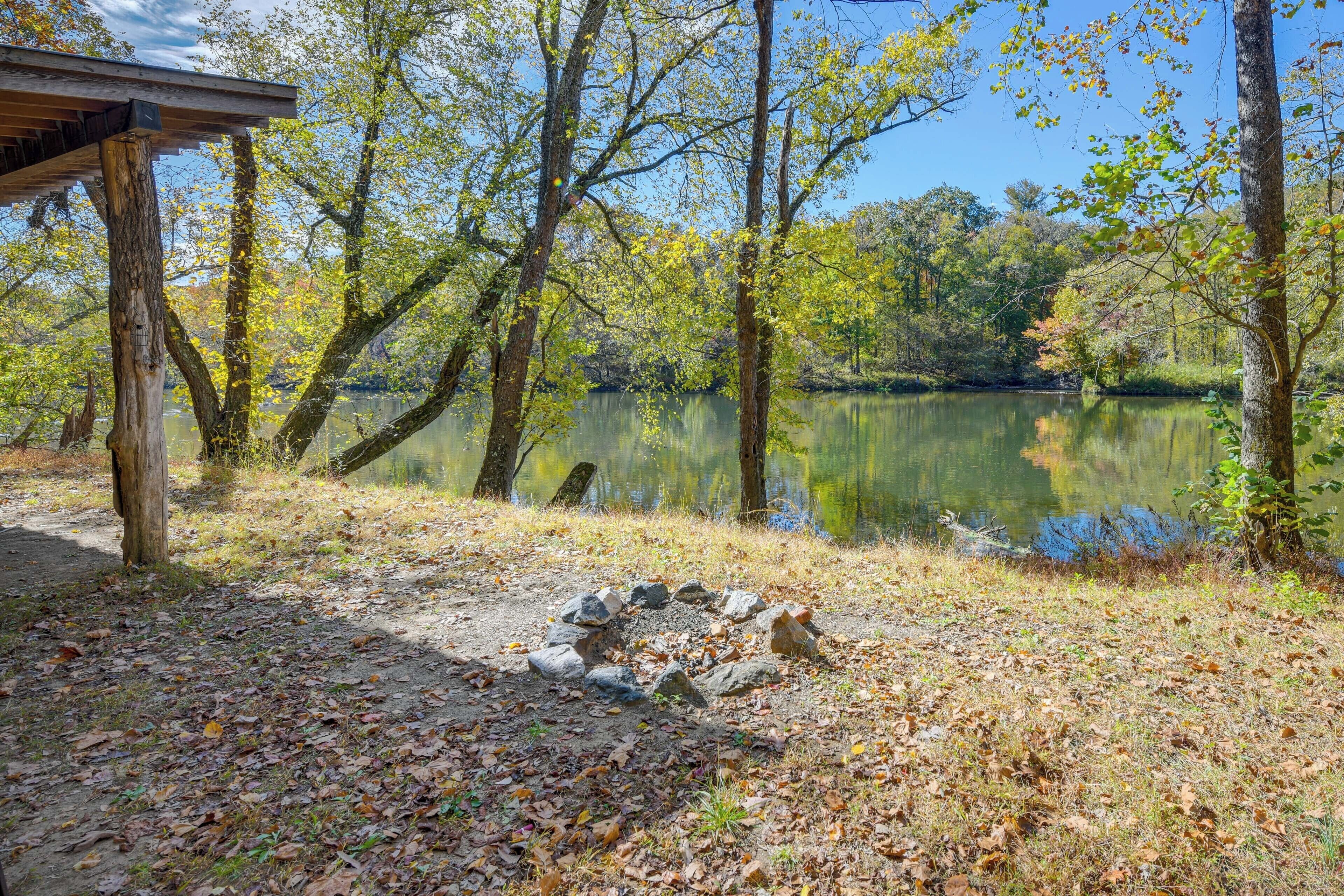A serene lakeside setting with a wooden deck and a stone fire pit.