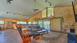 A spacious living area with a wooden ceiling, large windows, a sofa, a coffee table, and a wooden rocking chair. - Direct Hiking Access: Riverfront Dolores Home! (Dolores)