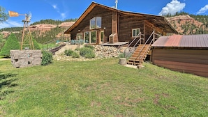A rustic wooden cabin with a stone foundation, a windmill, and a staircase leading to the entrance. - Direct Hiking Access: Riverfront Dolores Home! (Dolores)