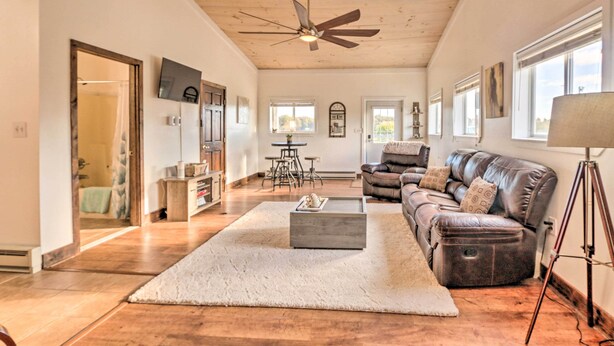 A spacious living room with a leather sofa, a coffee table, and a ceiling fan. - Equestrian Escape! Quiet Farm Stay Near Gettysburg (Union Bridge)