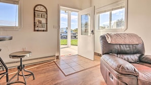 A room with a leather sofa, a small round table, a bench, and a door leading outside. - Equestrian Escape! Quiet Farm Stay Near Gettysburg (Union Bridge)