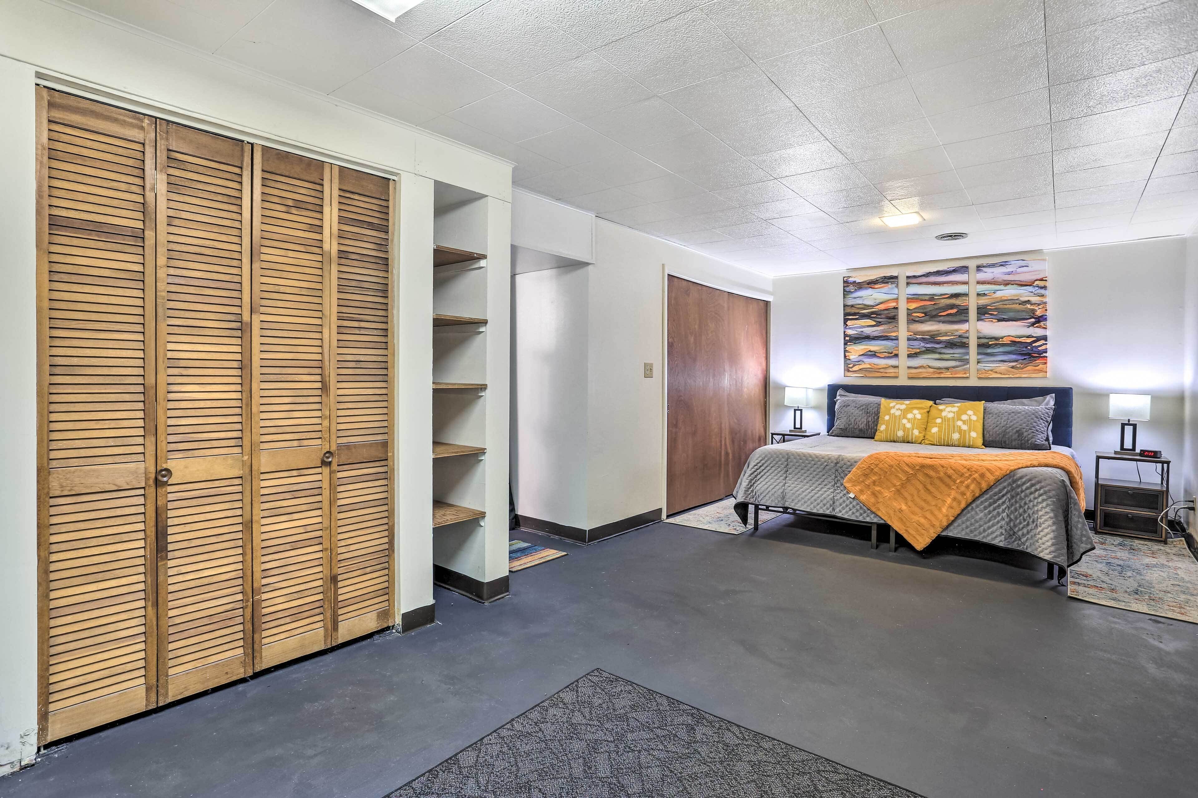 A bedroom with a bed, a wardrobe, a nightstand, and a wall art piece.
