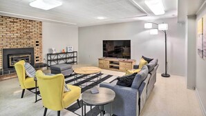 A modern living room with a brick fireplace, a sofa set, a coffee table, and a TV.