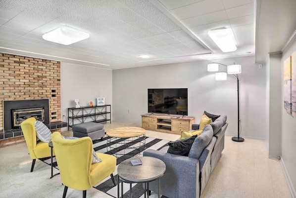 Uma sala de estar moderna com lareira de tijolos, televisão de tela plana e conjunto de sofás.