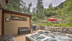 A hot tub on a wooden deck with a stone wall and a red umbrella in the background. - Family Home in Georgetown: Walk to Town & Railroad (Georgetown)
