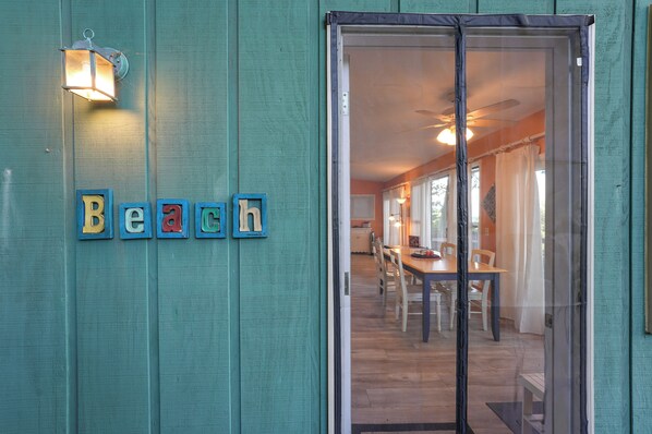 A room with a teal wall, a glass door, and a dining area visible through the door. - Family Friendly Mears Cottage - Walk to the Beach! (Mears)