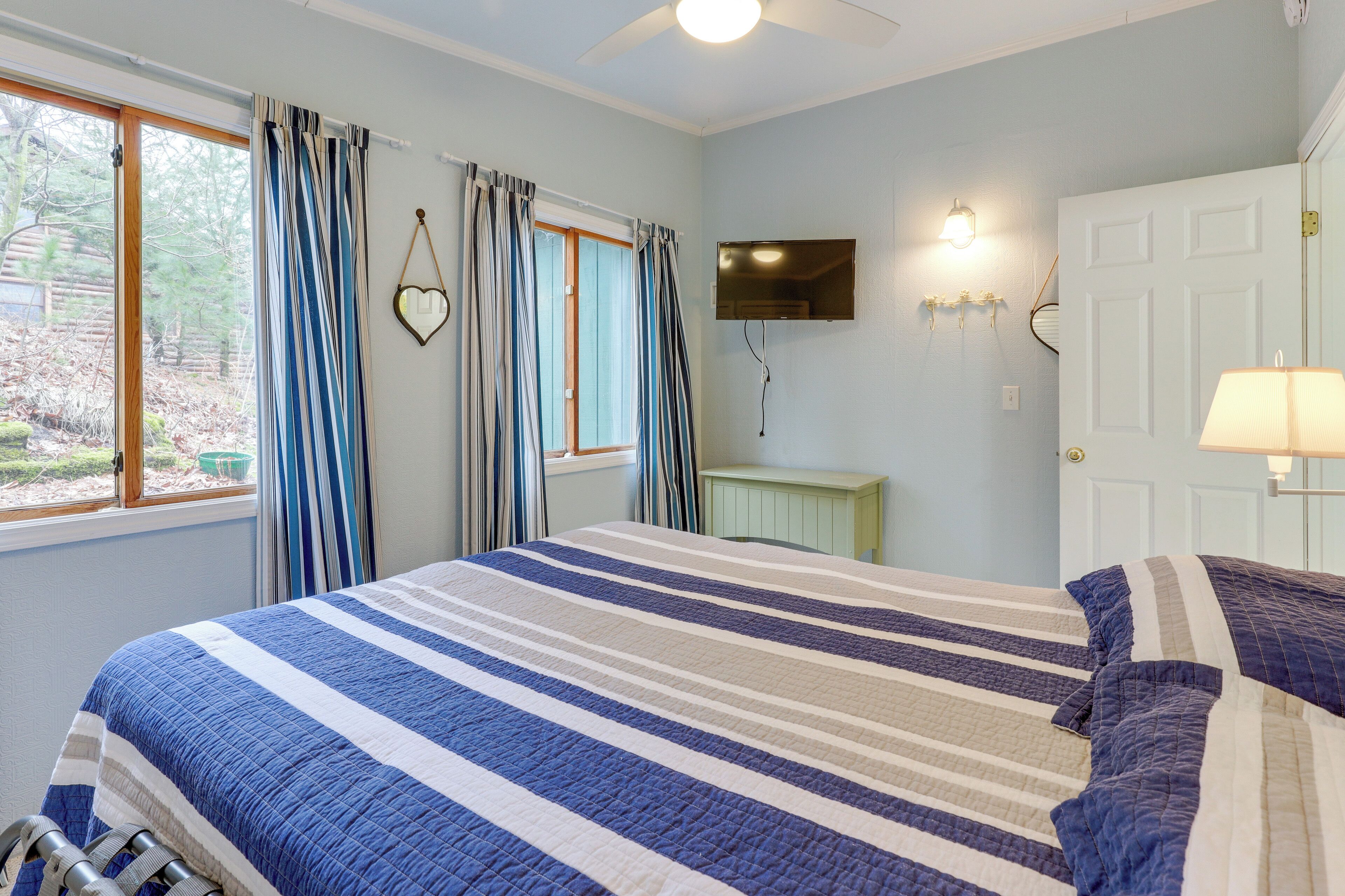 Une chambre à coucher avec un lit, des rideaux, une télévision et une lampe.