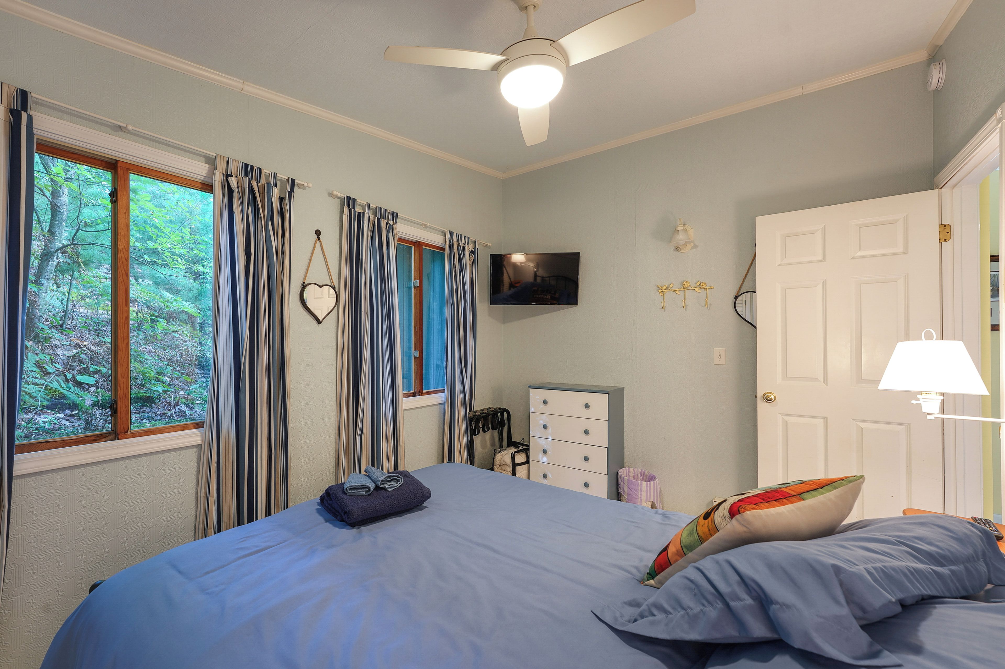 A bedroom with a bed, a television, a wardrobe, and a door.