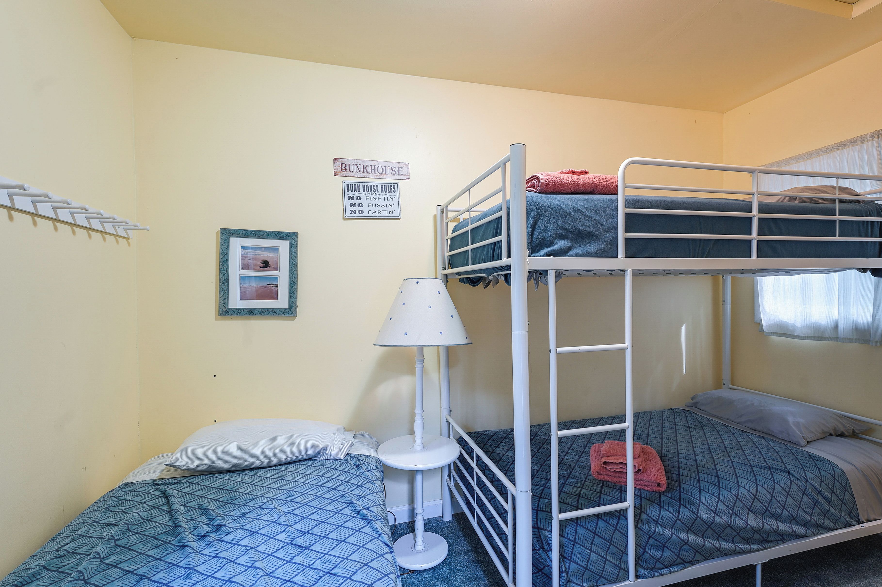 A bunk bed room with a bunkhouse sign, a lamp, and a framed picture on the wall.