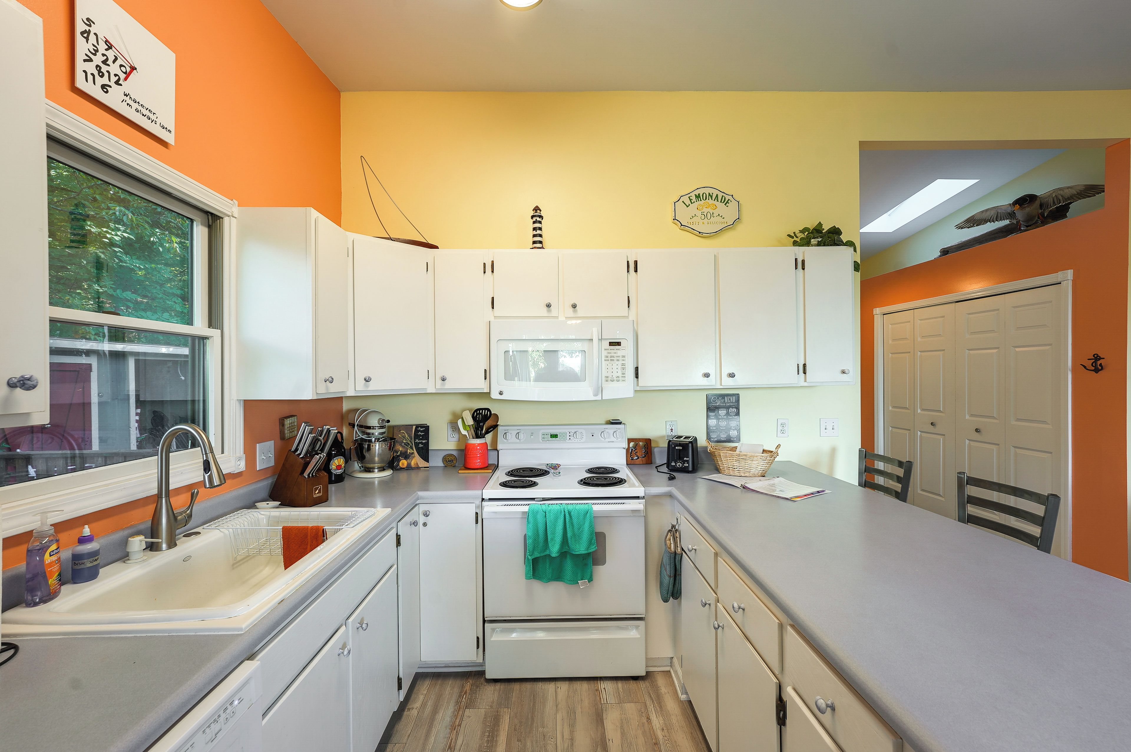 A kitchen with white cabinets, a microwave, a stove, and a sink.