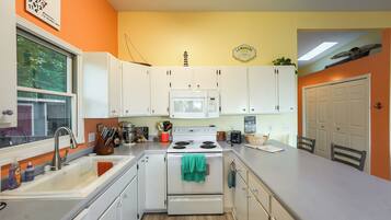 A kitchen with white cabinets, a microwave, a stove, and a sink.