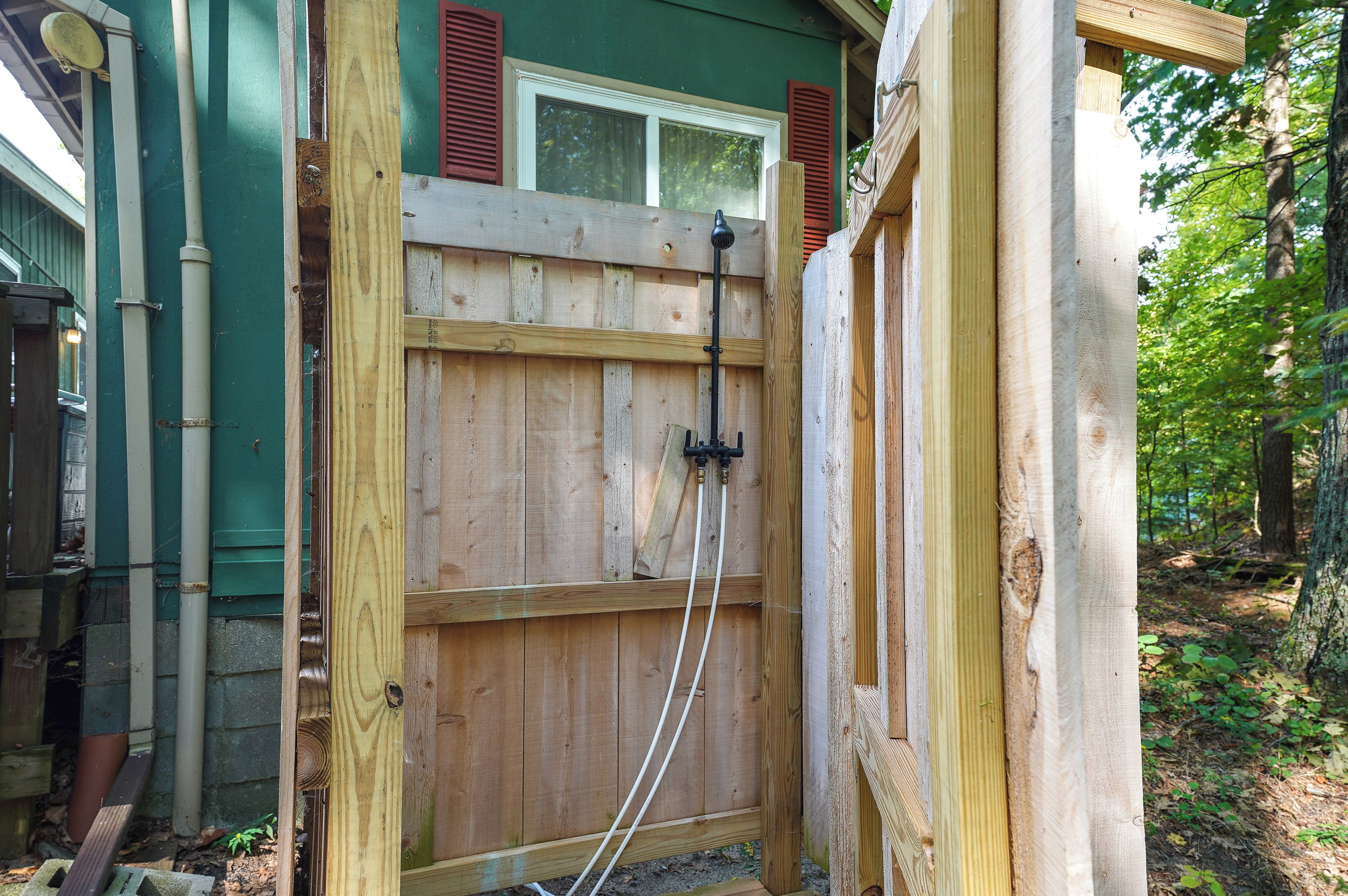 A wooden gate with a window above it, a wooden fence, and a green wall.