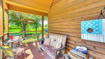 A wooden deck with a bench, a table with chairs, and a birdhouse.