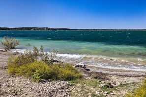 Un paisaje costero con agua cristalina, costa rocosa y vegetación escasa.