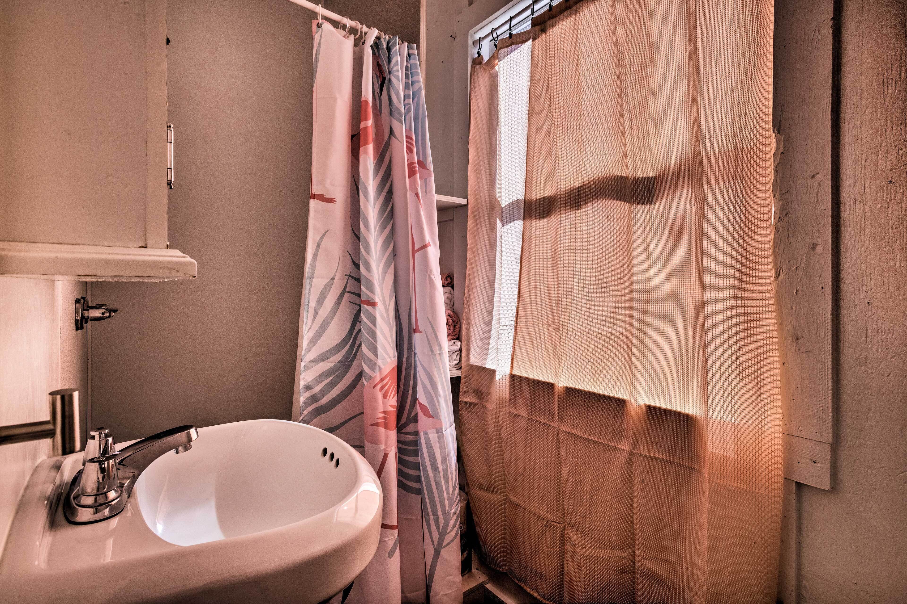 A bathroom with a sink, mirror, and shower curtain.