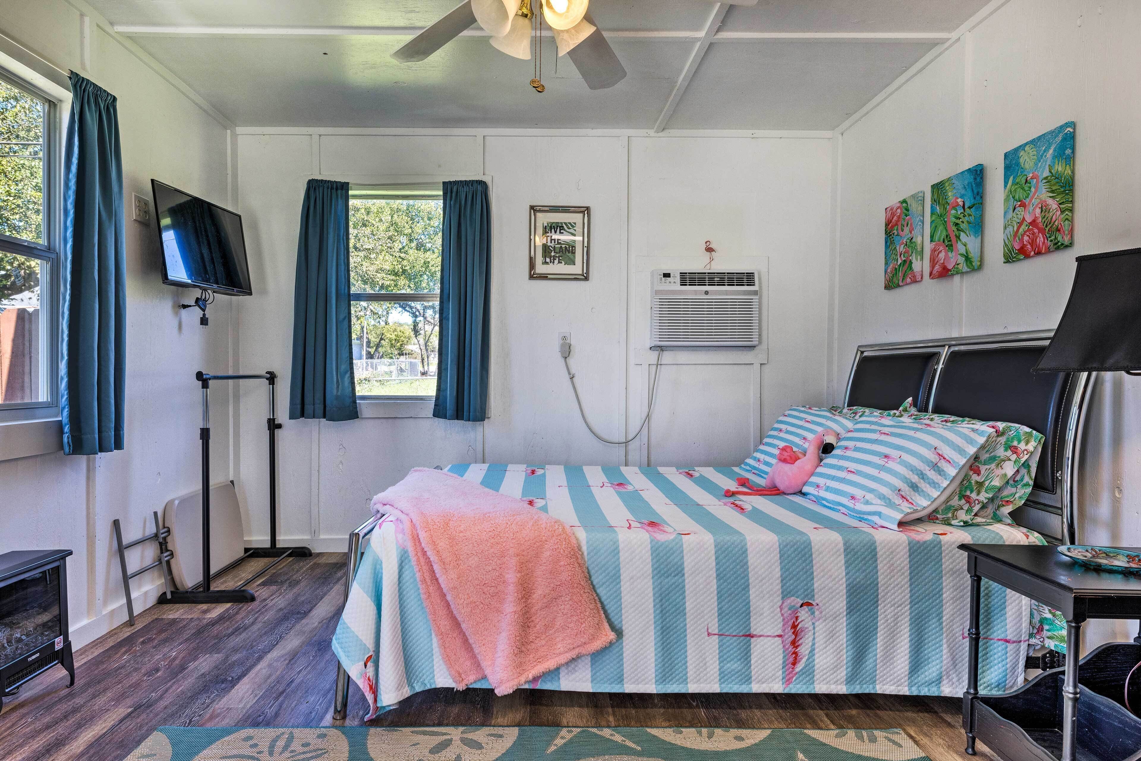 Une chambre à coucher avec un lit, une télévision, un climatiseur et des œuvres d’art accrochées au mur.