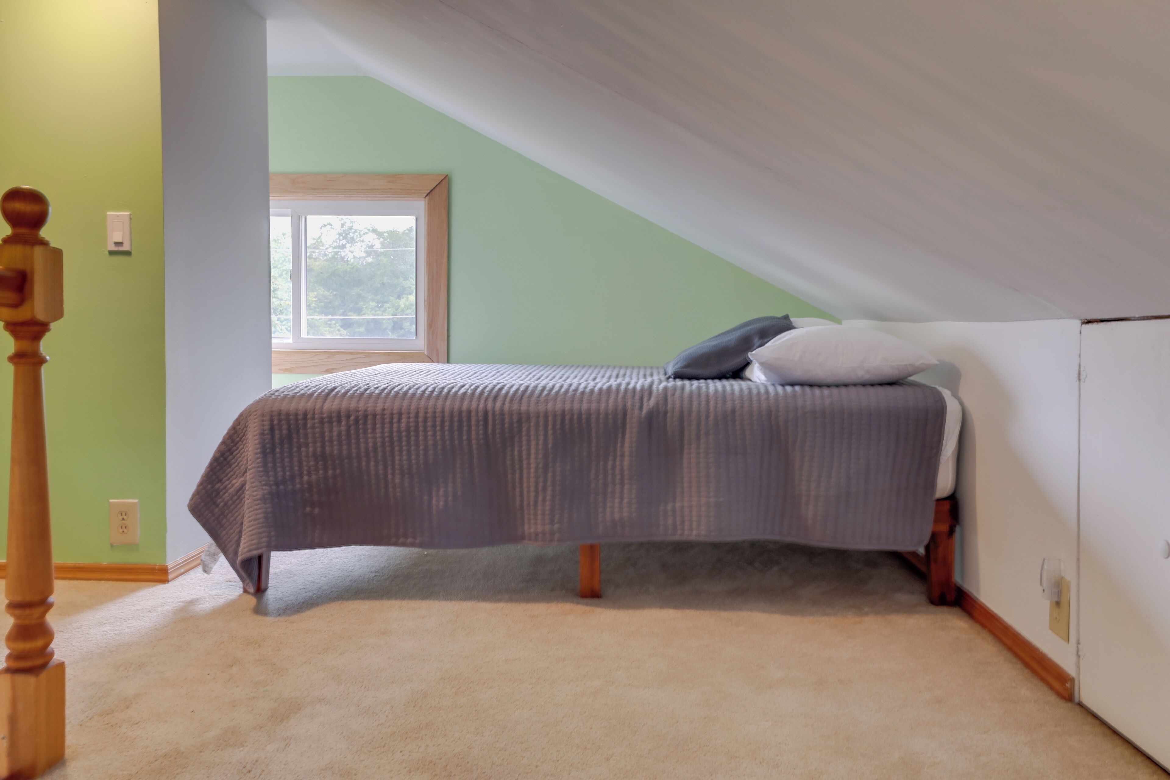 A bedroom with a bed, a window, and a door.