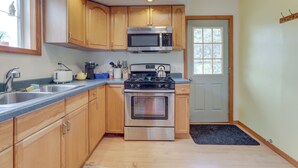 A modern kitchen with wooden cabinets, stainless steel appliances, and a built-in microwave.
