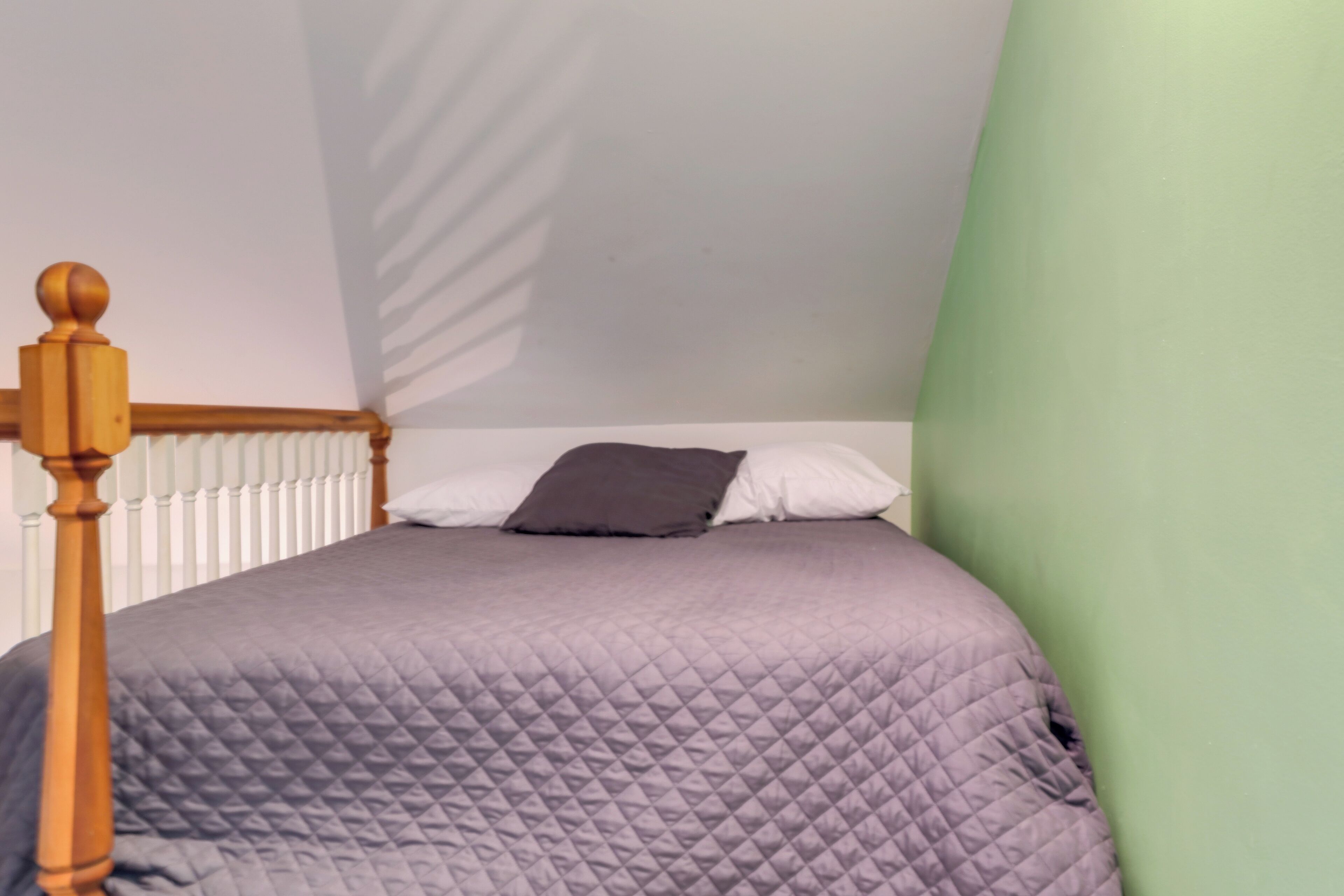 A bedroom with a bed, a wooden headboard, a white radiator, and a green wall.