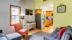A compact living space with a kitchenette, a dining area with a table and chairs, a sofa, and a staircase leading to an upper level.