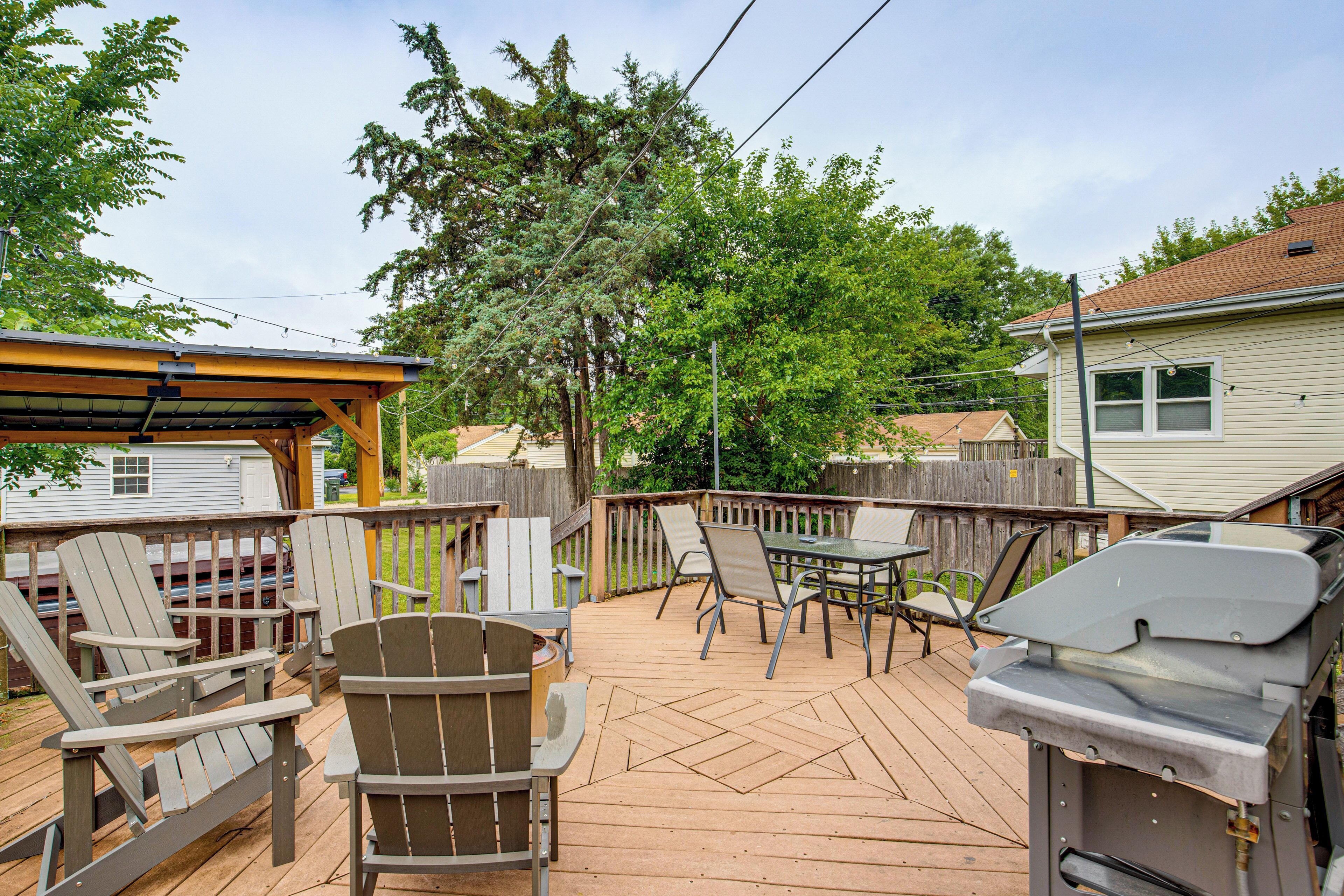 A wooden deck with Adirondack chairs, a barbecue grill, and a covered seating area.