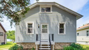 A two-story house with a front porch, a set of stairs leading to the entrance, and a small garden area.
