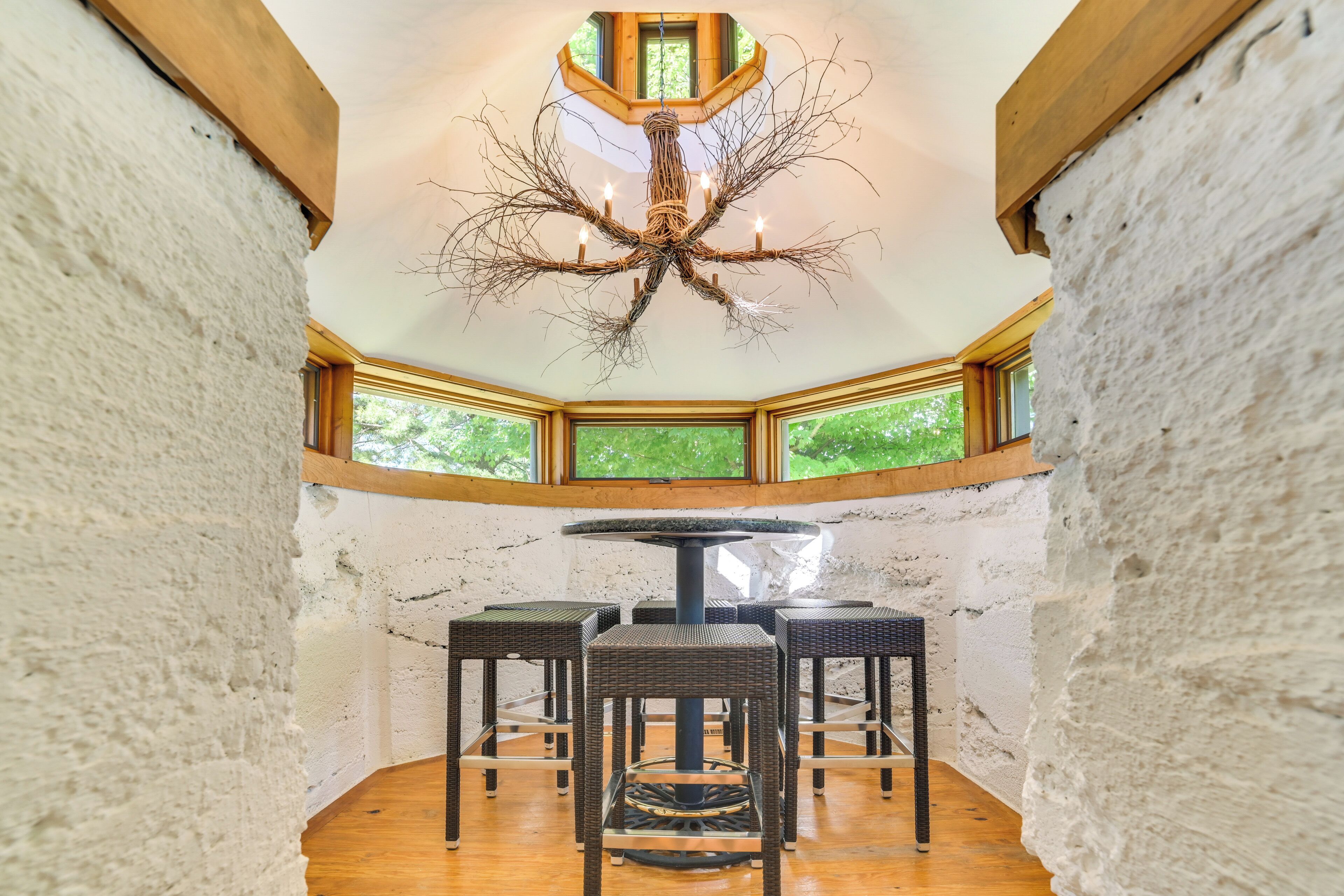 A room with a round table, four chairs, and a unique chandelier.