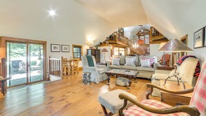 Un vaste salon doté d’un haut plafond, d’un plancher en bois, d’un grand canapé et d’un escalier menant à un niveau supérieur.