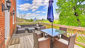 A wooden deck with wicker furniture and a glass table, overlooking a green landscape. - Historic 'hammond House' w/ Wine Country View! (Strasburg)