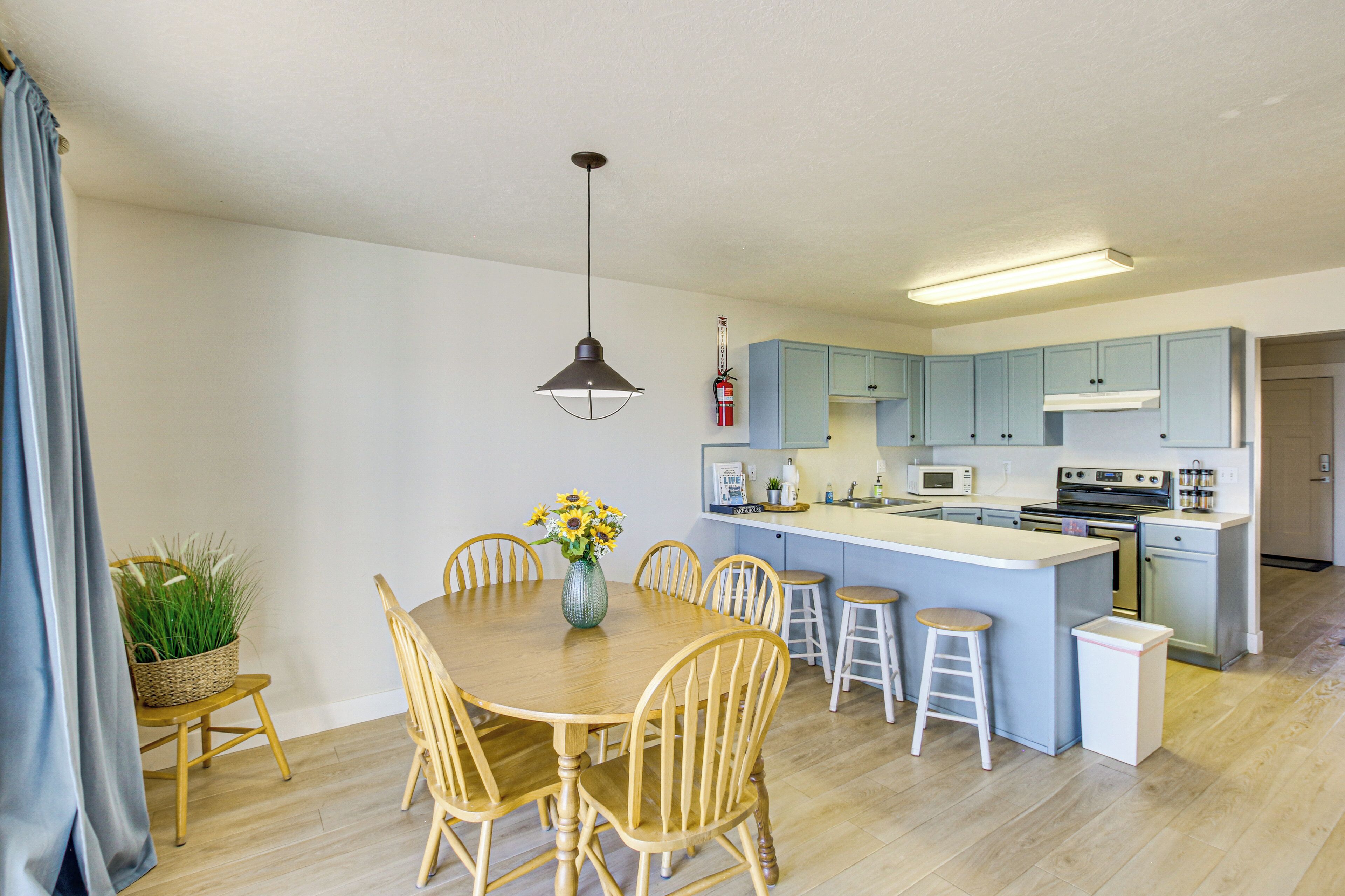 A modern kitchen with a central island, wooden chairs, and a dining table.