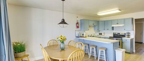 A modern kitchen with a central island, wooden chairs, and a dining table.