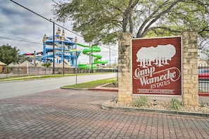 A sign for Camp Warnecke Estates Resort Condominiums with a water park in the background.