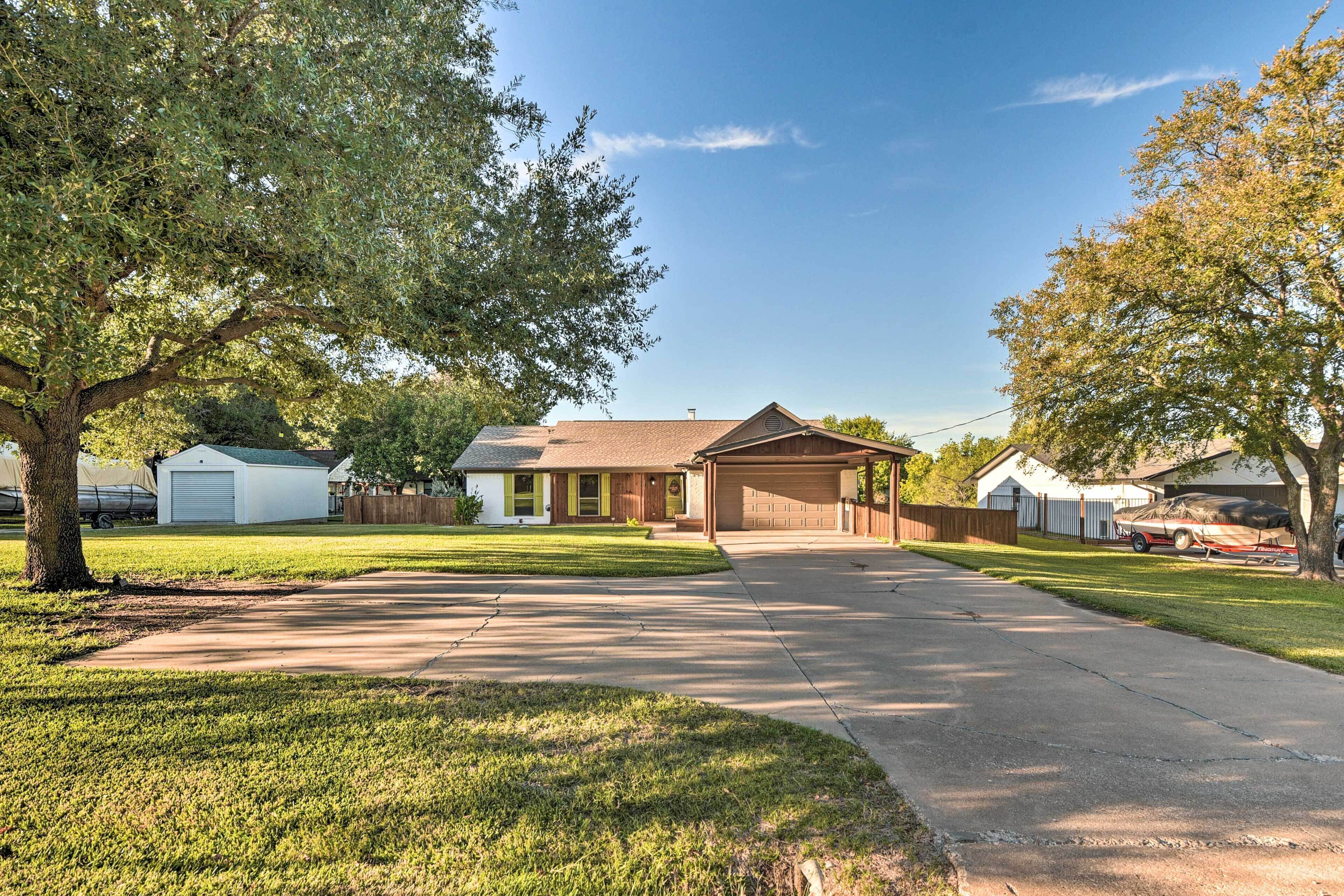 A residential driveway leading to a house with a garage, a covered porch, and a lawn.